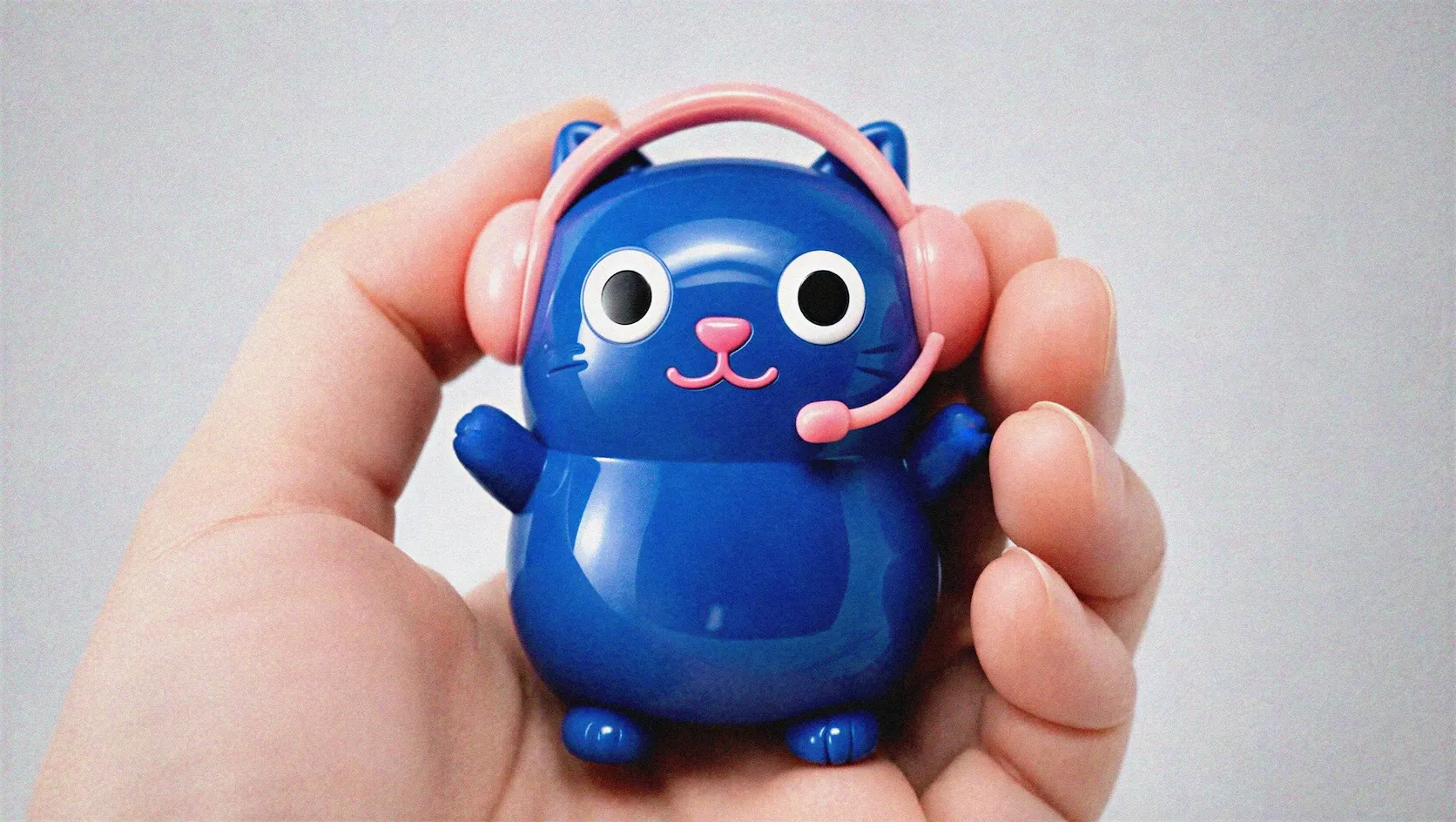 手掌中配戴粉色耳機的藍色 FIRST LINE 客服貓軟膠公仔